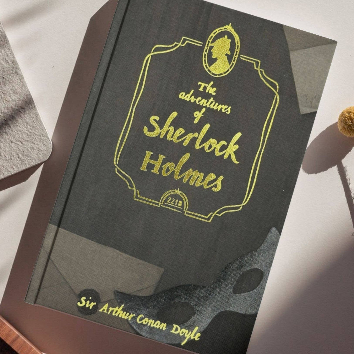 Book titled 'The Adventures of Sherlock Holmes' by Sir Arthur Conan Doyle on a light surface.