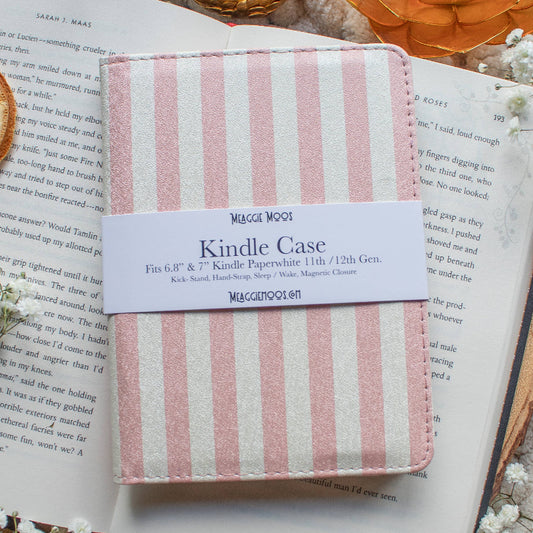 Pink striped Kindle case on an open book with decorative elements