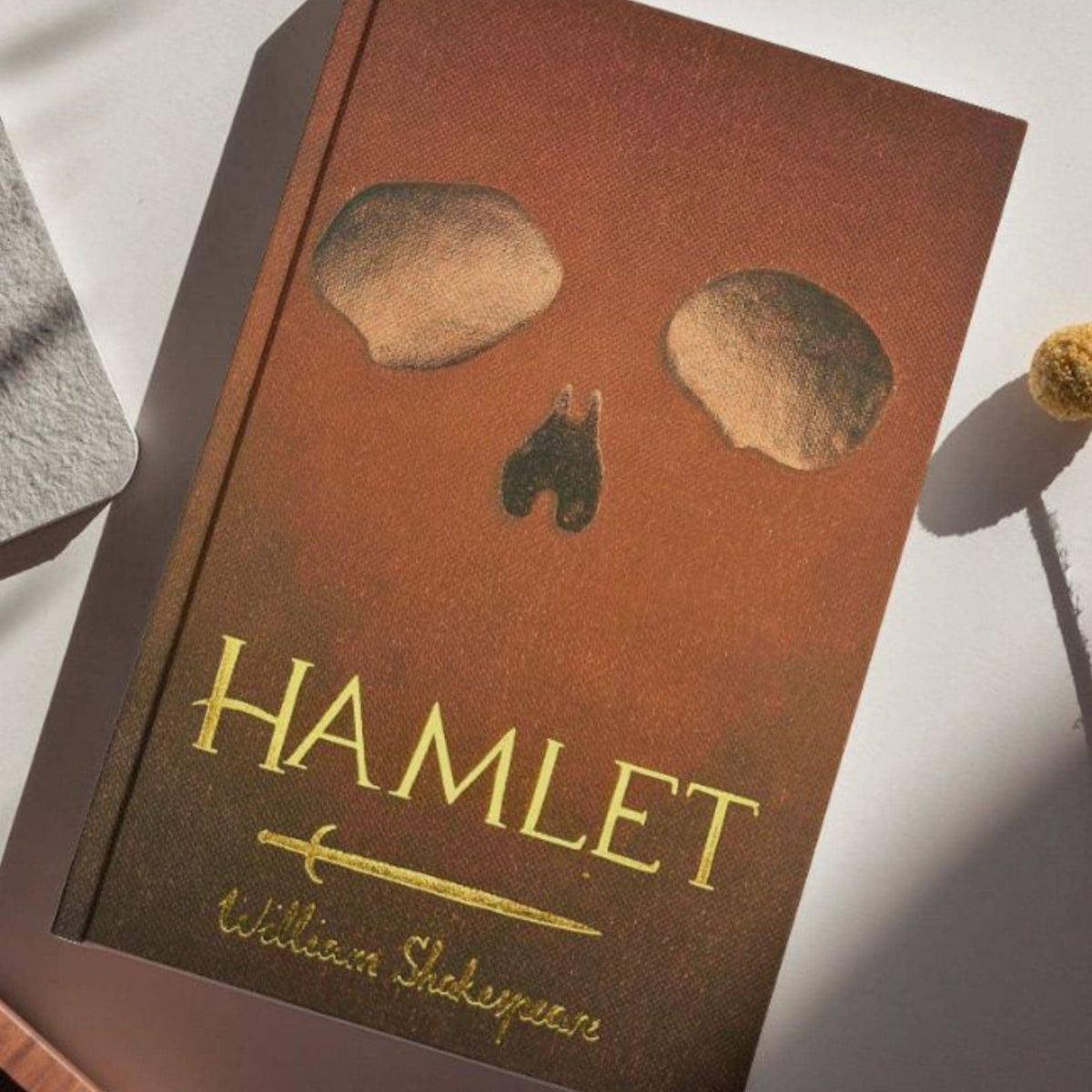 Book titled 'Hamlet' by William Shakespeare with a skull design on the cover.