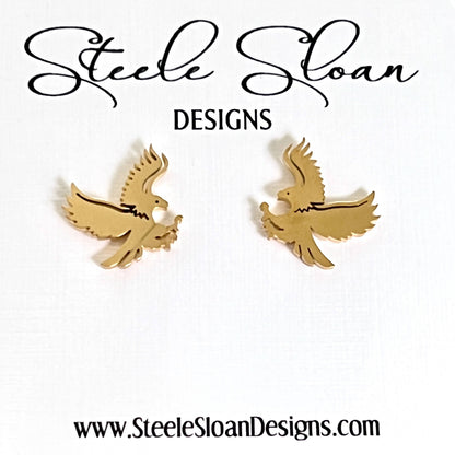 A pair of gold eagle-shaped stud earrings displayed on a white card with the brand name 'Steele Sloan DESIGNS' at the top and the website 'www.SteeleSloanDesigns.