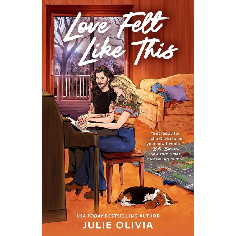 Book cover for 'Love Fell Like This' by Julie Olivia, featuring an illustrated couple sitting together in a warmly lit living room with a piano, orange walls, and a dog on the floor.