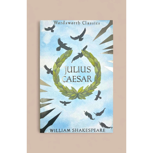A book cover for 'Julius Caesar' from the Wordsworth Classics series, featuring a light blue sky background with black birds flying around a green laurel wreath. The cover is centered on a solid beige background.
