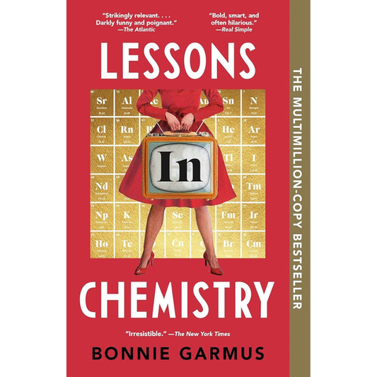 Book cover of 'Lessons Chemistry' by Bonnie Garmus, featuring a red background, a woman in a red dress holding a vintage television with the letter 'In' on its screen, and a gold periodic table backdrop. The title is in large white letters, and the author's name is at the bottom.