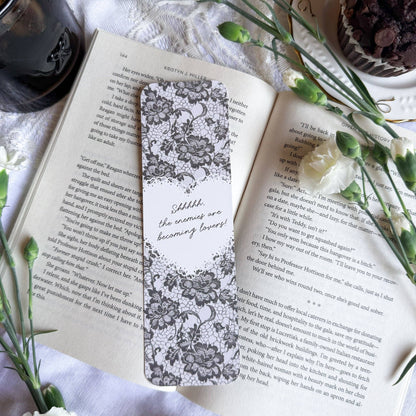 Open book with a decorative bookmark on a white surface with flowers and a cup.